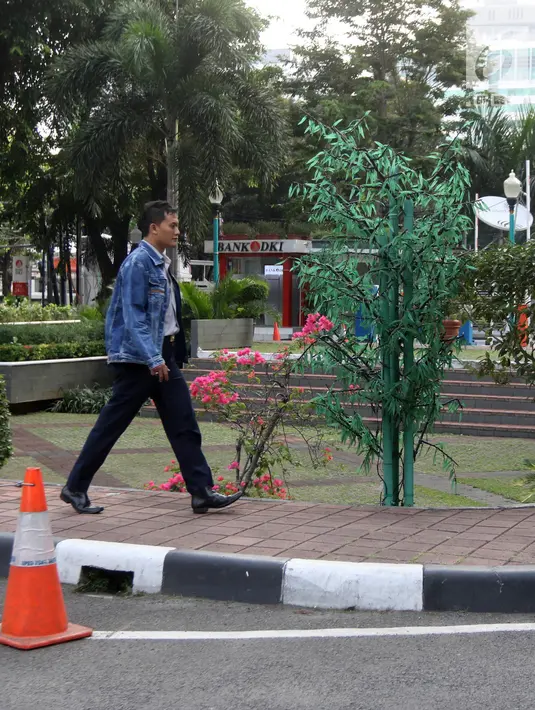 Seorang pegawai melintas di samping pohon imitasi yang terpasang di halaman Balai Kota DKI Jakarta, Senin (4/6). (Liputan6.com/Arya Manggala)