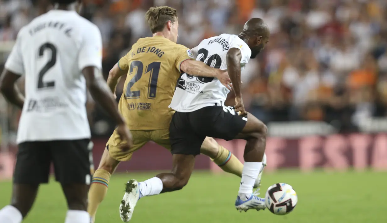Gelandang Barcelona Frenkie de Jong berebut bola dengan  bek Valencia Dimitri Foulquier pada jornada ke-12 La Liga 2022/23 di Mestalla, Minggu (30/10/2022) dini hari WIB. Berkat kemenangan ini Barcelona naik ke puncak klasemen La Liga dengan raihan 31 poin dari 12 laga. (AP Photo/Alberto Saiz)