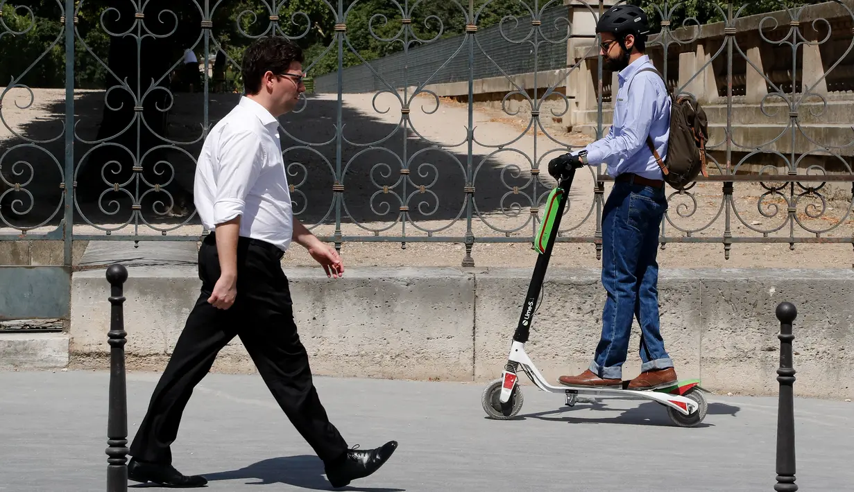 Seorang pria menggunakan skuter listrik saat beraktivitas di Paris, Prancis (9/7). Skuter listrik ini dibuat oleh perusahaan AS Lime yang merupakan penyewaan transportasi sepeda dan skuter di berbagai kota. (AFP Photo/Francois Guillot)