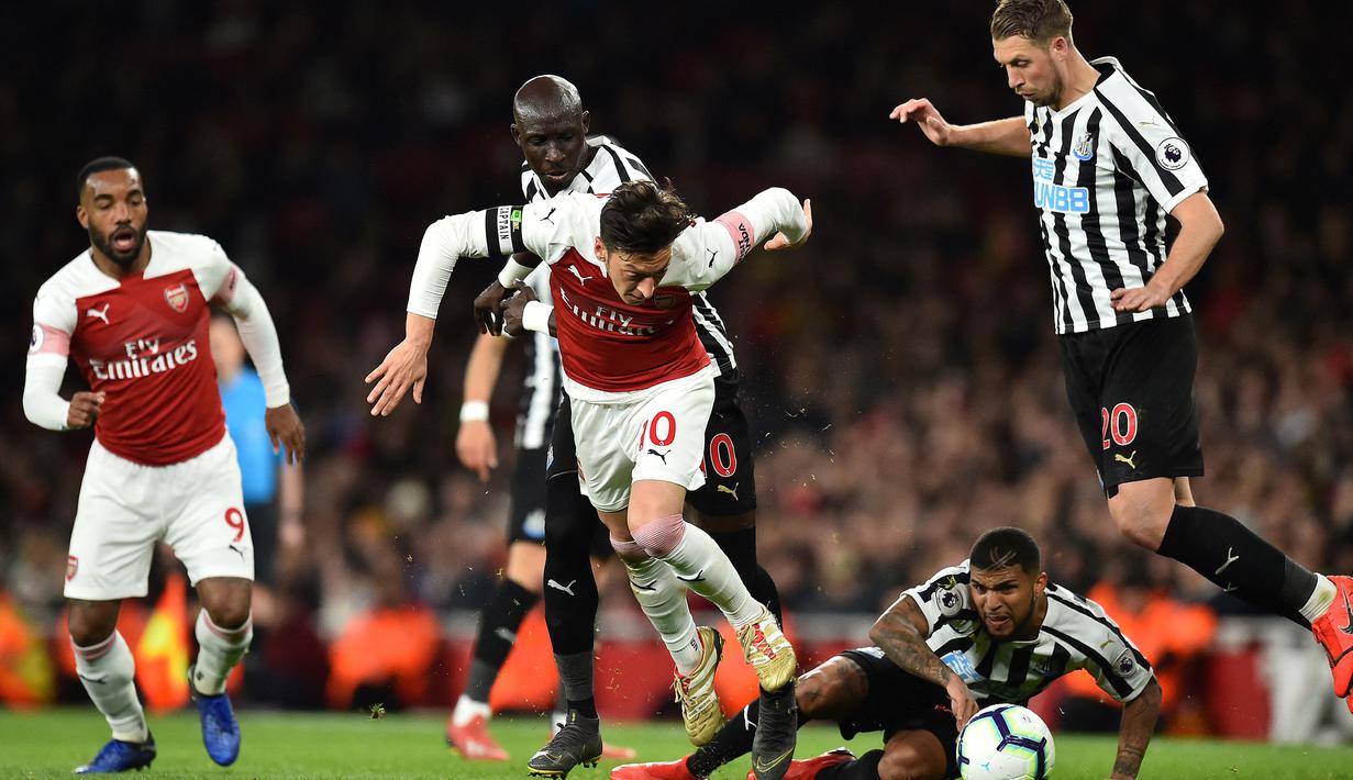 Gelandang Arsenal, Mesut Oezil (tengah) dikepung tiga pemain Newcastle United pada laga Liga Inggris 2018/2019 di Emirates Stadium, London (1/4/2019). Mesut Oezil tercatat membuat 4 gol dan 1 assist ke gawang Newcastle United saat berseragam Arsenal dari total 6 laga di Liga Inggris sejak musim 2013/2014 hingga 202/2021. (AFP/Glyn Kirk)