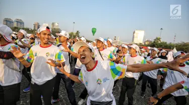 Warga mengikuti gerakan senam sembari menunggu prosesi Torch Relay Asian Games 2018 di Jakarta, Sabtu (18/8). Hari ini merupakan puncak kirab obor Asian Games 2018 dimana api abadi akan berlabuh di Gelora Bung Karno. (Liputan6.com/Faizal Fanani)