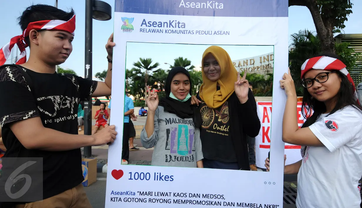 Warga berpose saat mendukung aksi Relawan Komunitas Peduli ASEAN di Jakarta, Minggu (13/3/2016). Relawan ini mengajak masyarakat menggunakan kaos bergambar tentang ke-Indonesia-an dan memposting ke seluruh media sosial. (Liputan6.com/Helmi Fithriansyah)