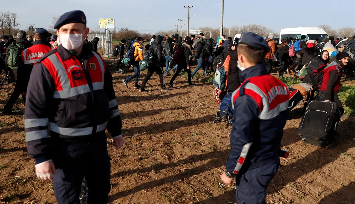 Para migran melewati polisi Turki dekat perbatasan Turki dengan Yunani di Gerbang Pazarkule, Edirne, Turki, Selasa(3/3/2020). (AP Photo/Darko Bandic)