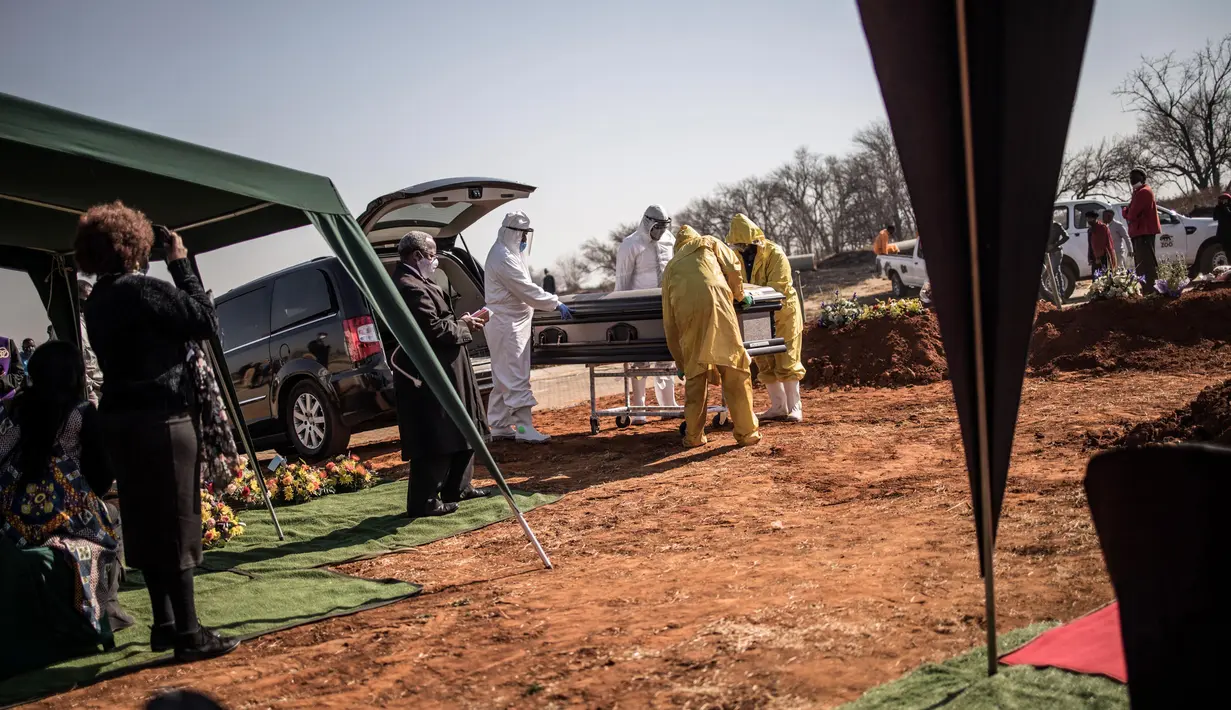 Para pengurus dari rumah duka AVBOB mendorong peti mati selama pemakaman jenazah pasien virus corona COVID-19 di pemakaman Olifantsvlei, Soweto, Afrika Selatan, 21 Juli 2020. (MARCO LONGARI/AFP)