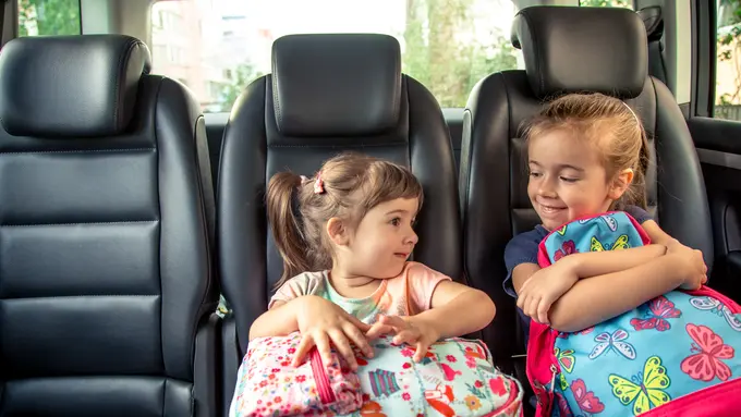 Dua orang anak perempuan memegang tas ransel di dalam mobil (Foto Dok: Freepik/pvproductions)