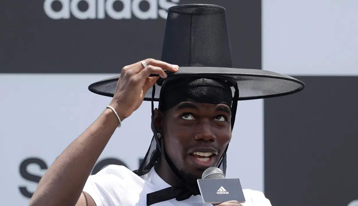 Gelandang Manchester United, Paul Pogba marapikan topi tradisional Korea Selatan saat jumpa pers di Seoul, Korea Selatan, Kamis (13/6/2019). Paul Pogba berada di Seoul sebagai bagian dari tur Asia-nya. (AP Photo/Lee Jin-man)