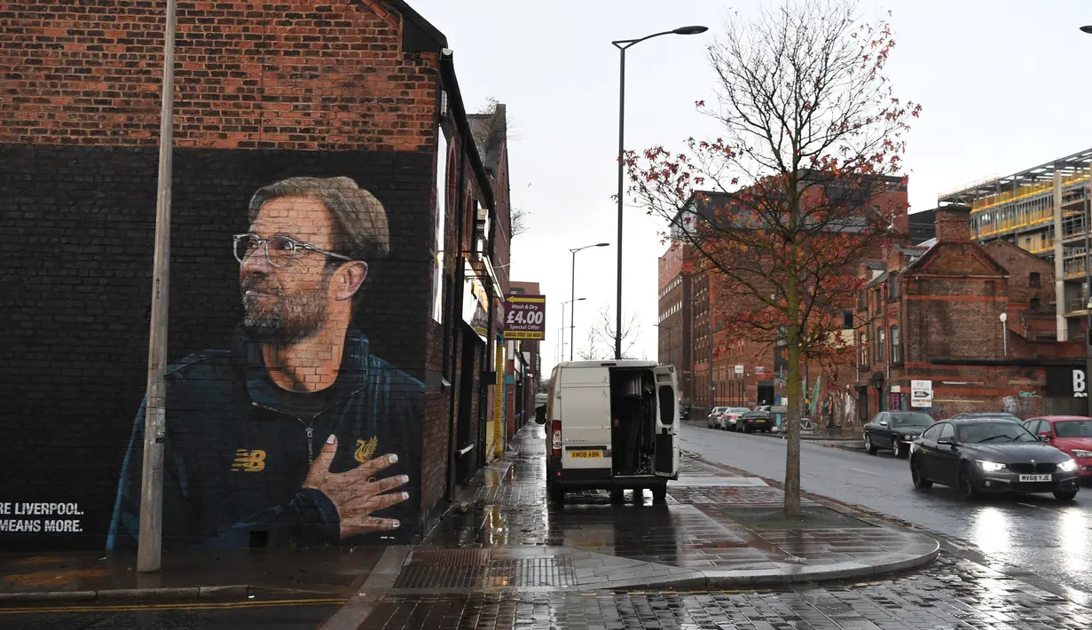 Kendaraan melintas dekat mural pelatih klub Liverpool, Jurgen Klopp di Jamaica Street, pusat kota Baltic Triangle di Liverpool, Senin (10/12). Pengerjaan mural tersebut dimulai sejak Sabtu, 8 November lalu oleh seniman jalanan "Akse". (Paul ELLIS / AFP)