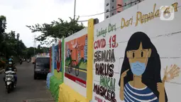 Warga melintas di depan mural yang berisi pesan 3M di Jakarta, Rabu (11/11/2020). Mural tersebut dibuat untuk mengingatkan masyarakat agar menerapkan protokol kesehatan saat beraktivitas sehari-hari. (Liputan6.com/Herman Zakharia)