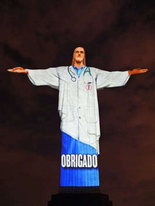 Patung Christ the Redeemer atau Yesus sang Penebus yang populer di dunia menyala dengan gambar seragam dokter bertuliskan 'Terima Kasih' pada hari Paskah di Rio de Janeiro, Brasil, Minggu (12/4/2020). Pertunjukkan itu bentuk dukungan dan semangat untuk melawan pandemi COVID-19. (CARL DE SOUZA/AFP)