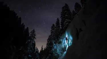 Anggota tim Arnica, Pierre mendaki tebing es saat sesi latihan malam hari di dekat La Lecherette, Hongrin, Kota Vaud, Swiss, Rabu (14/2). Pierre mendaki di bawah malam yang penuh bintang. (Anthony Anex/Keystone via AP)