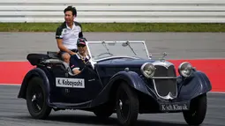 Kamui Kobayashi, pembalap Formula Satu asal Jepang ikut berparade mengelilingi Sirkuit Hockenheim menggunakan mobil antik, (20/7/2014). (REUTERS/Michael Dalder)