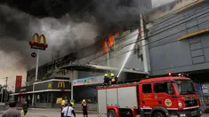 Petugas pemadam kebakaran menyiramkan air berusaha memadamkan api saat terjadi kebakaran di kota Davao, Filipina Selatan (23/12). Dalam insiden kebakaran ini dilaporkan 40 orang tewas. (AP Photo / Manman Dejeto)