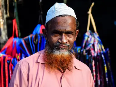 Dalam gambar yang diambil pada 24 Desember 2018, penjual sayur bernama Siddikur Rahman berpose dengan janggut oranye di Dhaka. Belakangan ini, pria-pria Muslim Bangladesh keranjingan berpenampilan dengan janggut warna-warna terang seperti merah hingga oranye. (MUNIR UZ ZAMAN / AFP)
