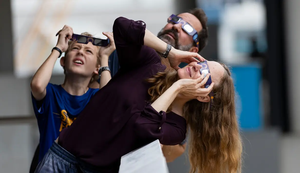 Gianluca Mazzuca (12), Nick Mazzuca, dan Elizabeth Mazzuca (kanan) menyaksikan Gerhana Matahari Cincin Api dari Frost Science Museum di Miami, Amerika Serikat, Sabtu (14/10/2023). Gerhana Matahari Cincin Api muncul pada 14 Oktober 2023 malam selama 5 menit 17 detik. (Matias J. Ocner/Miami Herald via AP)