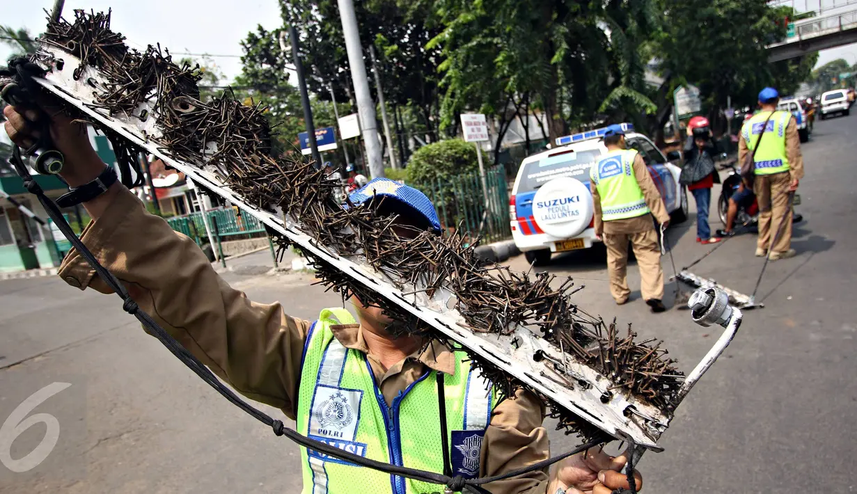 Petugas menunjukan paku yang dikumpulkan saat aksi giat sapu bersih ranjau paku di Jalan Kyai Tapa, Jakarta, Jumat (6/11). Aksi itu untuk membersihkan jalan dari ranjau paku yang disebarkan oknum tak bertanggung jawab. (Liputan6.com/Immanuel Antonius)