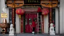 Seorang pekerja yang mengenakan masker membersihkan lentera berdebu di luar restoran di distrik perbelanjaan Wangfujing, Beijing, China, Rabu (14/12/2022). Mulai hari ini, Komisi Kesehatan Nasional China melaporkan penurunan kasus harian COVID-19 sejak pemerintah melonggarkan pengujian PCR setelah kasus harian mencapai rekor tertinggi. (AP Photo/Andy Wong)