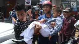 Petugas Damkar dari Pos Pesanggrahan membawa murid TK, Fathur  usai menyelamatkannya dari terjepit kaca pintu ATM Bank BNI di Jalan M. Saidi, pesanggrahan, Jakarta Selatan, Senin (5/8/2019). Fathur mengalami luka pada tanggannya selanjutnya dibawa ke rumah sakit. (merdeka.com/Arie Basuki)