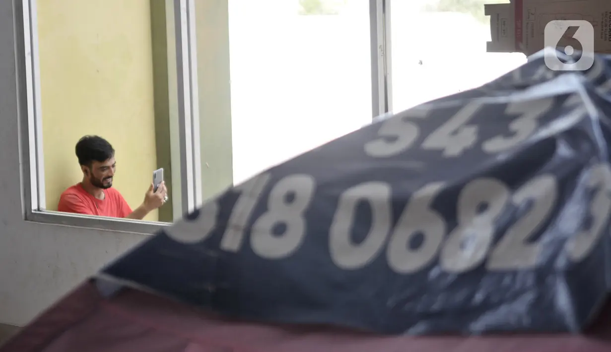 Seorang imigran pencari suaka menelepon kerabatnya saat berada di penampungan sementara di Kalideres, Jakarta, Rabu (18/12/2019). Para imigran hanya menggunakan listrik untuk mengisi baterai telepon selular lantaran dayanya tidak cukup untuk penerangan gedung. (merdeka.com/Iqbal Nugroho)