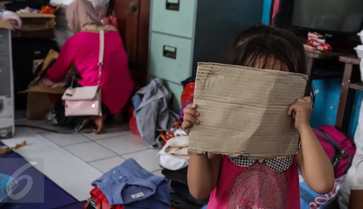 Seorang anak korban kebakaran tengah menutupi muka dengan kardus saat diambil gambar di dalam kelas SD Kristen Fajar Sion, Jakarta Barat, Minggu (8/1). Lebih dari 600 korban kebakaran tinggal di ruang kelas Gereja Fajar Sion. (Liputan6.com/Fery Pradolo)