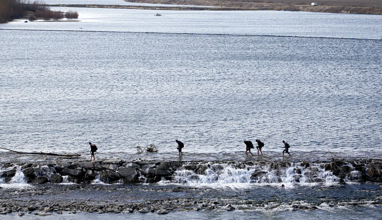 Para migran menyeberangi Sungai Maritsa dalam perjalanan mereka ke perbatasan Yunani di Edirne, Turki, Selasa (3/3/2020). Turki secara resmi mengumumkan dibukanya perbatasan bagian barat bagi migran dan pengungsi yang berharap dapat menuju ke Uni Eropa. (AP Photo/Darko Bandic)
