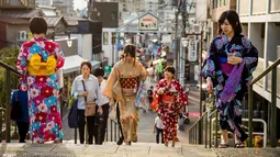 Sejumlah wanita memakai pakaian tradisional berjalan di sepanjang jalan perbelanjaan Yanaka Ginza di pusat Tokyo (30/9/2019). Wilayah Yanaka di ibukota Jepang dikenal sebagai salah satu yang paling kuno dan unik. (AFP Photo/Odd Andersen)