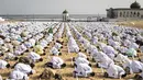 Pengikut komunitas Layene Senegal melaksanakan salat Ied selama perayaan Tabaski (Idul Adha) di lingkungan populer Yoff di Dakar, Rabu (21/7/2021). Bendera putih kecil yang tertancap di atas pasir pantai Yoff terpasang sebagai penanda jaga jarak antar jemaah. (JOHN WESSELS / AFP)