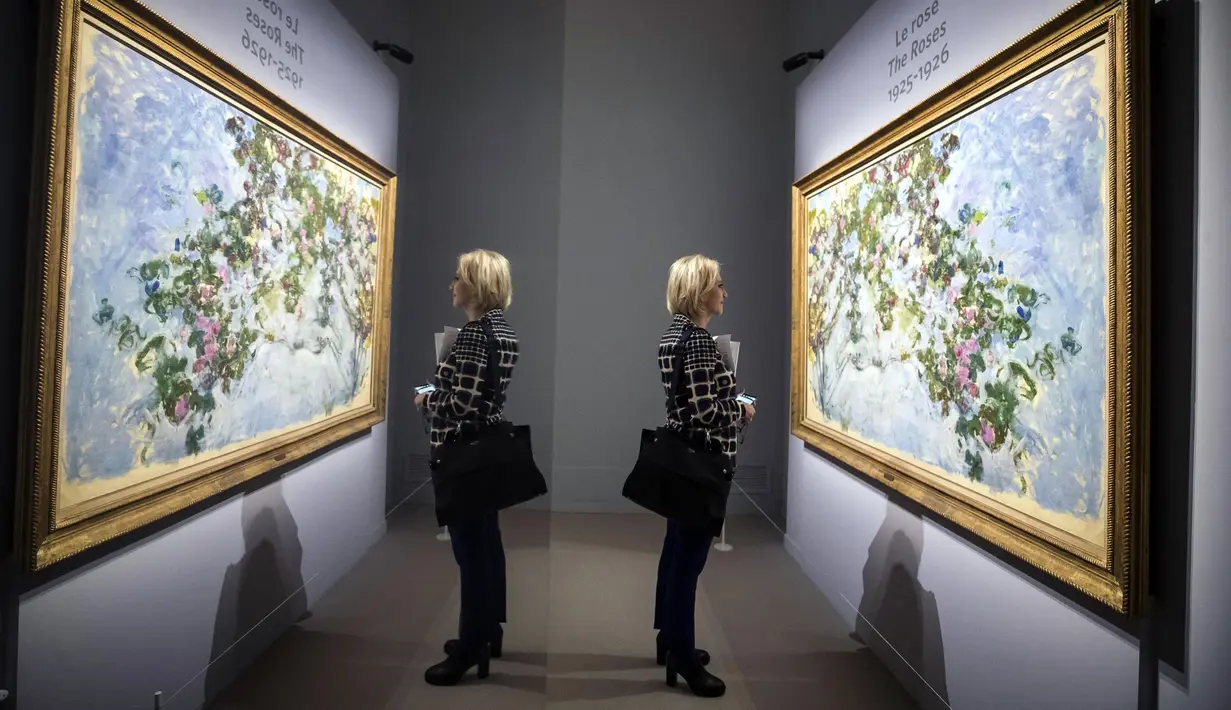 Refleksi dari cermin yang menggambarkan seorang wanita melihat lukisan Claude Monet 'The Roses' saat pameran 'Monet. Capolavori dal Musee Marmottan' di Roma, Italia (18/10). (Angelo Carconi / ANSA via AP)