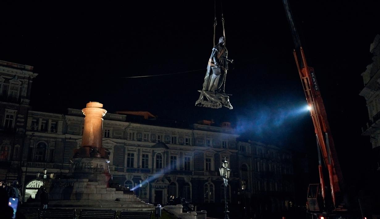 Para pekerja memindahkan monumen untuk Catherine II yang juga dikenal sebagai "Monumen Pendiri Odesa" di Odesa, Ukraina, 29 Desember 2022. Keputusan untuk membongkar monumen yang terdiri dari patung Permaisuri Rusia Catherine II dan rekannya dibuat baru-baru ini oleh penduduk Odesa melalui pemungutan suara elektronik. (AP Photo/LIBKOS)