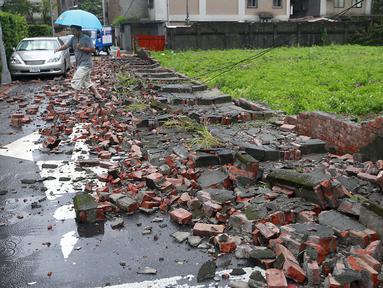 Seorang pria berjalan di antara reruntuhan batu bata sebuah dinding yang hancur akibat Topan Matmo, Taiwan, Rabu (23/7/14). (REUTERS/Pichi Chuang)