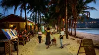 Karyawan restoran mengundang orang yang lewat saat para turis memanfaatkan program "Kotak Pasir Phuket" untuk pengunjung yang divaksinasi penuh terhadap virus corona Covid-19 di pulau Phuket Thailand (25/10/2021). (AFP/Mladen Antonov)