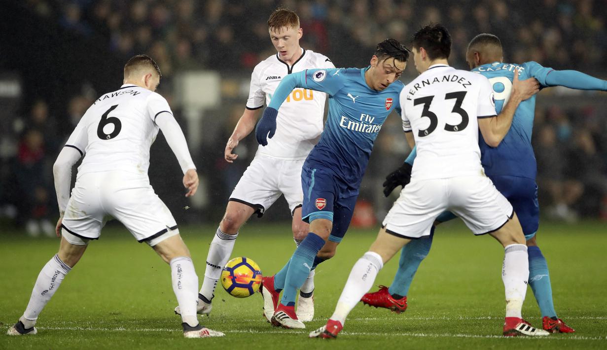 Aksi pemain Arsenal, Mesut Ozil (tengah) menerobos pertahanan Swansea City pada lanjutan Premier League di Liberty Stadium, Swansea, Wales, (30/1/2018). Arsenal kalah 1-3. (Nick Potts/PA via AP)