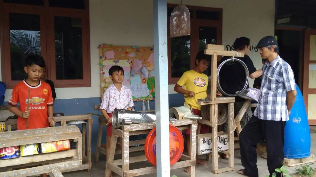 Kepala SD Kanisius Kenalan Onesimus Maryono (kanan bertopi) sedang memerhatikan anak-anak didiknya bermain musik dari kaleng (blek) (Foto: Dokumentasi SDK Kenalan)