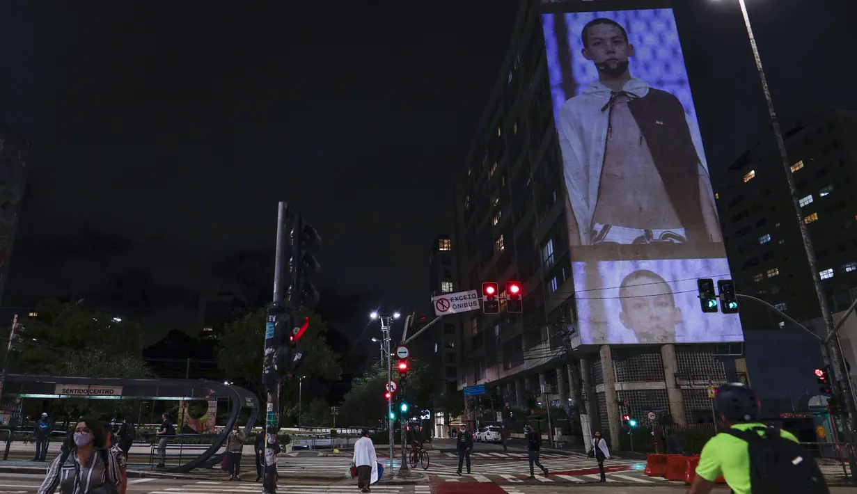 Model mengenakan kreasi dari koleksi Alexandre Herchcovitch yang diproyeksikan pada sebuah gedung selama Sao Paulo Fashion Week, Rabu (4/11/2020). Perancang busana meninggalkan catwalk dan mengandalkan teknologi digital untuk memamerkan karya koleksi spring/summer mereka. (AP Photo/Marcelo Chello)