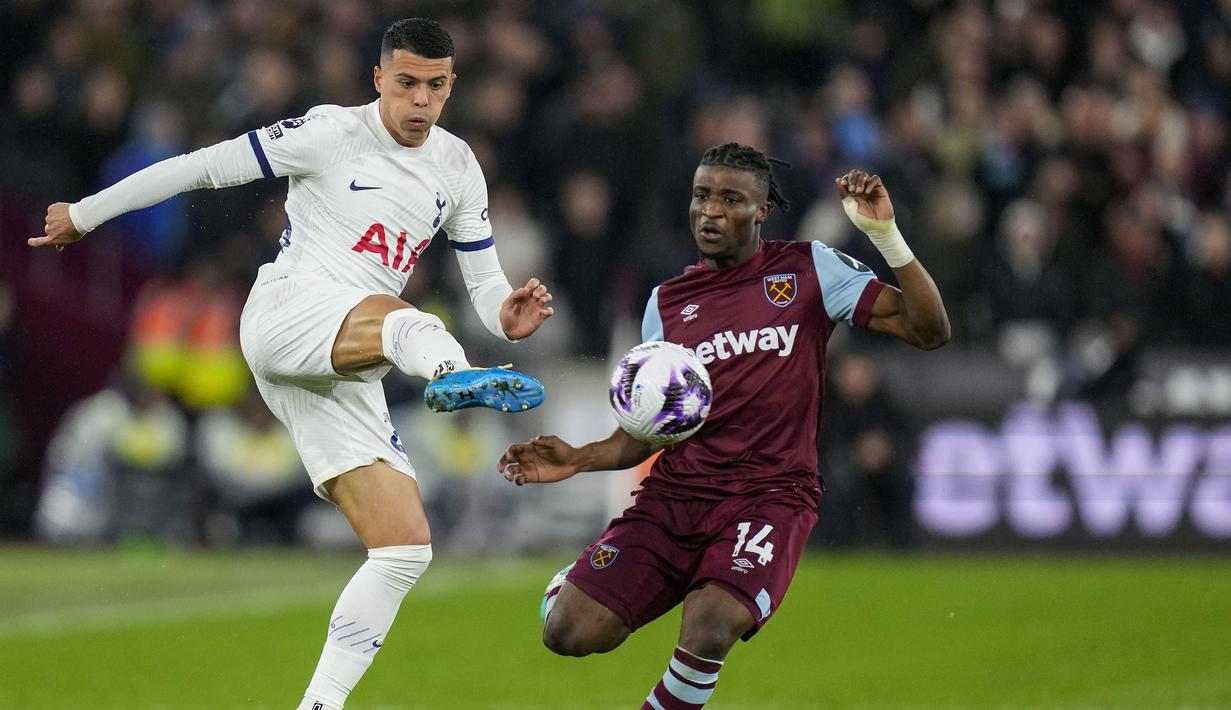 Bek Tottenham Hotspur, Pedro Porro (kiri) melepaskan tendangan di depan gelandang West Ham United, Mohammed Kudus pada laga pekan ke-31 Premier League 2023/2024 di London Stadium, London, Selasa (2/4/2024) malam. (AP Photo/Kirsty Wigglesworth)