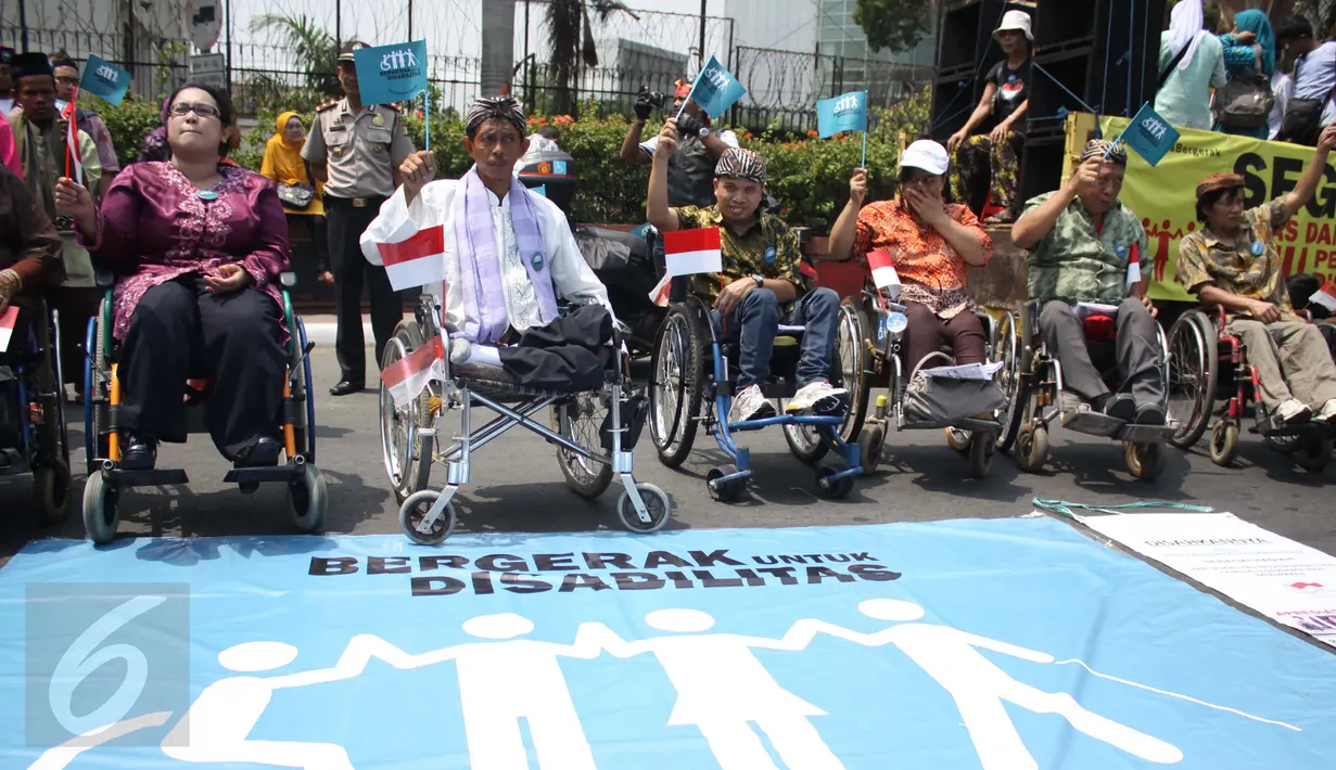 Penyandang disabilitas melambaikan bendera bertuliskan ‘Bergerak untuk Disabilitas’ saat Karnaval Budaya Disabilitas di kawasan Bundaran HI, Jakarta, Selasa (18/08/2015). (Liputan6.com/Gempur M Surya)  