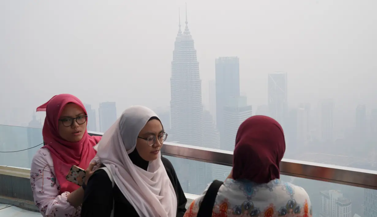 Wisatawan memandang kota dari Kuala Lumpur Tower saat kabut asap menyelimuti Kuala Lumpur, Malaysia, Rabu (18/9/2019). Badan Meteorologi Klimatologi dan Geofisika (BMKG) mendeteksi sebaran asap akibat kebakaran hutan dan lahan di Sumatra mencapai Malaysia dan Singapura. (AP Photo/Vincent Thian)
