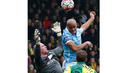 Pemain Manchester City, Vincent Kompany (tengah) berusaha menyundul bola dari hadangan kiper Norwich, John Ruddy (kiri) pada lanjutan liga Inggris pekan ke-30 di Stadion Carrow Road, Norwich, Sabtu (12/3/2016). (AFP/Lindsey Parnaby)