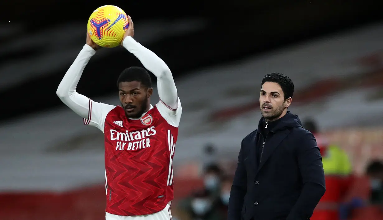 Gelandang Arsenal, Ainsley Maitland-Niles bersiap melakukan lemparan ke dalam di depan pelatih Mikel Arteta saat menghadapi Southampton dalam laga Liga Inggris 2020/2021 di Emirates Stadium, London (16/12/2020). Meski Ainsley Maitland-Niles telah dipromosikan ke tim utama Arsenal pada awal musim 2017/2018, nyatanya ia lebih banyak dipinjamkan ke beberapa klub. Kini ia tengah dipinjamkan ke Southampton sejak awal musim 2022/2023. (AFP/Pool/Peter Cziborra)
