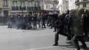 Polisi anti huru hara Prancis melemparkan tabung gas air mata ke arah pengunjuk rasa perayaan May Day di Paris, Senin (1/5). Seorang perwira polisi Prancis mengalami luka bakar dan dua lainnya luka-luka dalam bentrokan tersebut. (Zakaria ABDELKAFI/AFP)