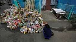Seorang wanita berdoa untuk orban Penikaman Massal yang terjadi di Kawasaki, Jepang (29/5/2019). Korban tewas dalam penikaman ini bertambah menjadi dua orang. Pelaku sendiri tewas usai menikam dirinya. (Reuters/Issei Kato)