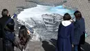 Sejumlah warga melihat sebuah karya ilusi optik 3-D yang bergambar kota Aleppo yang hancur akibat perang di kampus Universitas Meiji di Tokyo, Jepang (18/11). Karya ini ditampilkan untuk menimbulkan rasa kemanusiaan di Jepang. (AFP/Toshifumi Kitamura)