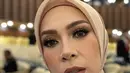 Ia melengkapi penampilannya dengan bros emas dari @subeng klasik. Serta hijab segi empat warna coklat muda yang selaras dengan bawahannya.  [@melly_goeslaw].