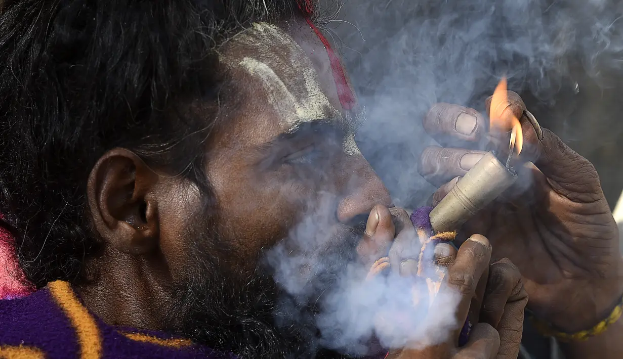 Seorang Sadhu atau orang suci Hindu menghisap ganja menggunakan 'chillum', pipa tanah liat tradisional, menjelang festival Hindu 'Maha Shivaratri', di Kathmandu (9/3/2021). Festival ini juga menandai hari penyempurnaan pernikahan Siwa. (AFP/Prakash Mathema)
