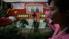 Pemandu memberi isyarat di depan potret pemimpin Korea Utara, Kim Il Sung dan Kim Jong Il pada pameran bunga 'Kimjongilia' di Pyongyang, Kamis (14/2). Korea Utara menggelar festival bunga merayakan ulang tahun mendiang ayah Kim Jong-un. (Ed JONES/AFP)