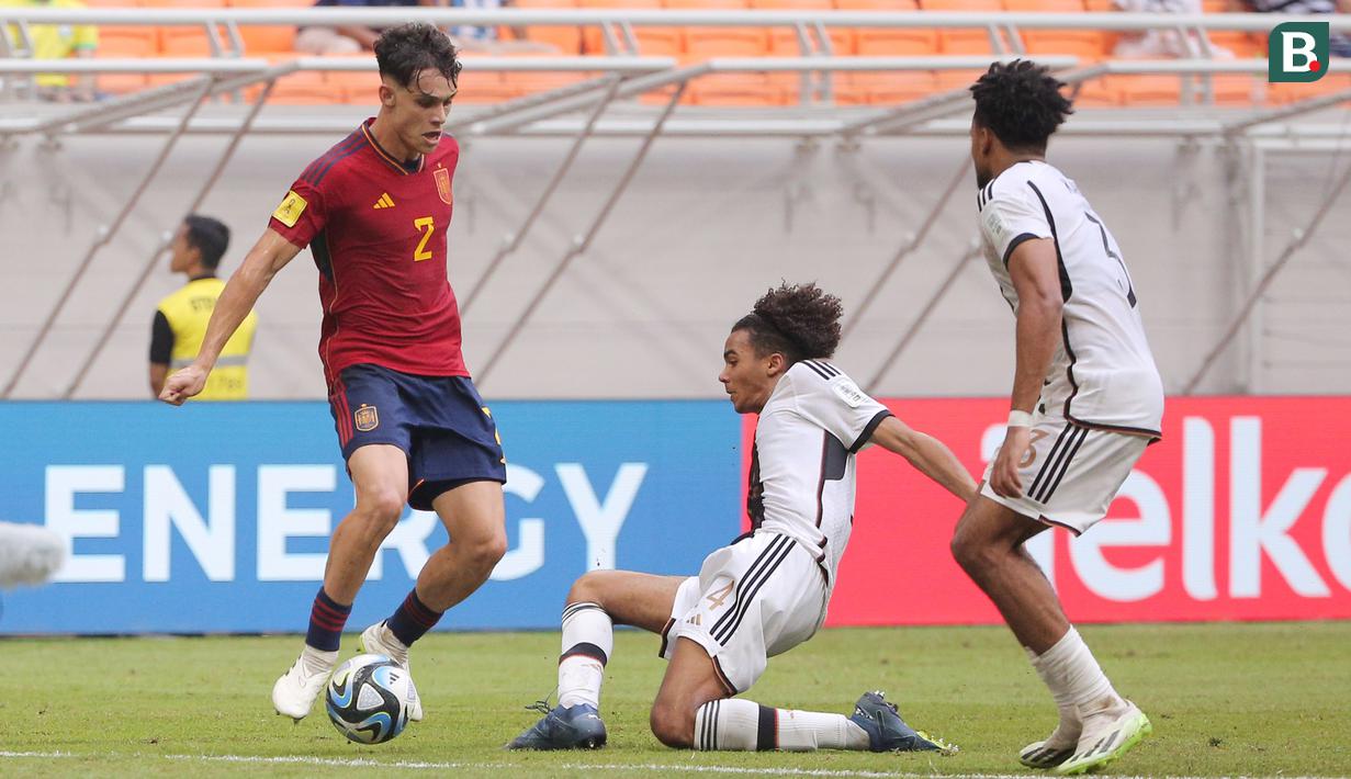<p>Pemain Timnas Jerman U-17, David Odogu (tengah), berusaha menghentikan laju dari pemain Spanyol U-17,&nbsp;Hector Fort (kiri) saat pertandingan perempat final Piala Dunia U-17 2023 yang berlangsung di Jakarta International Stadium, Jumat (24/11/2023). (Bola.com/M Iqbal Ichsan)</p>