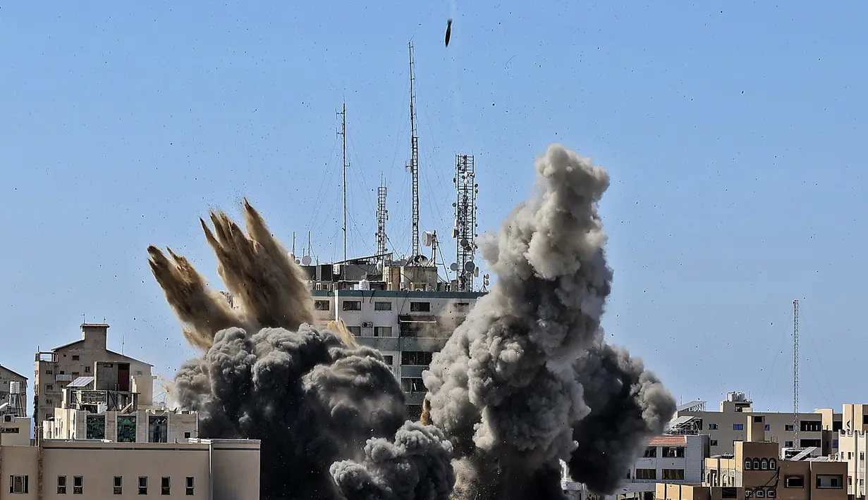 Asap mengepul dari gedung yang menampung berbagai media internasional, termasuk The Associated Press, setelah serangan udara Israel di Kota Gaza, Sabtu (15/5/2021). Serangan terjadi satu jam usai militer Israel memerintahkan orang-orang untuk mengungsi dari gedung. (Mahmud Hams/Pool Photo via AP)