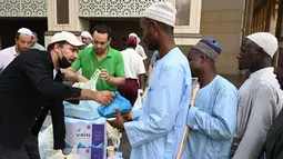 Penduduk Makkah membagikan makanan, buah-buahan, dan air mineral ke setiap orang yang lewat. (Sajjad HUSSAIN/AFP)