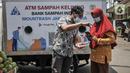 Petugas mendampingi warga saat memindai sampah botol melalui aplikasi smartphone sebelum ditabung ke ATM Sampah Keliling di kawasan Semper Barat, Cilincing, Jakarta Utara, Selasa (12/10/2021). (merdeka.com/Iqbal S. Nugroho)