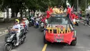 Sejumlah pemain Malut United menaiki mobil bak terbuka saat mengikuti konvoi di Kota Ternate, Maluku Utara pada Kamis (14/03/2024). (Bola.com/Hery Kurniawan)