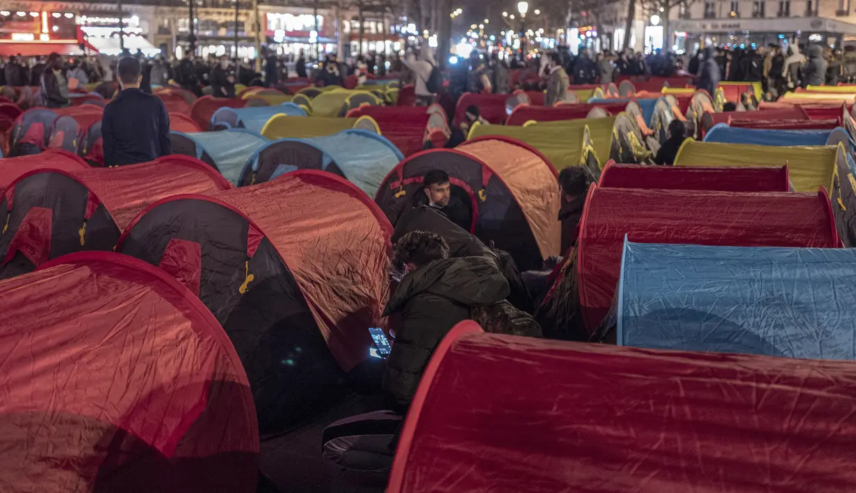 Aktivitas para migran di tenda yang mereka dirikan di Republic square, pusat kota Paris, pada Kamis (25/3/2021). Hampir 400 tenda didirikan di alun-aun tersebut untuk menarik perhatian atas kondisi kehidupan mereka dan menuntut akomodasi. (AP Photo/Rafael Yaghobzadeh)